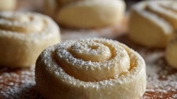 Freshly baked lemon rolls drizzled with sweet glaze, arranged on a plate with lemon slices.