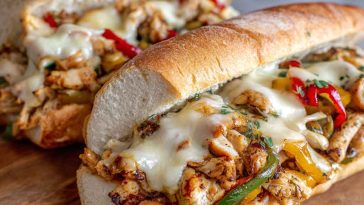 Ultimate Chicken Philly Cheese Steaks Recipe with juicy sliced chicken, sautéed onions and peppers, melted cheese, served in toasted hoagie rolls.