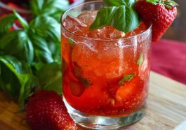 Refreshing strawberry basil smash cocktail made with fresh strawberries, basil leaves, lime juice, and ice in a glass, garnished with herbs and fruit.