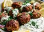 Baked Greek lentil meatballs served with creamy tzatziki sauce, fresh herbs, and a side of vegetables.