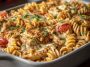 “Baked Cajun chicken pasta with creamy sauce, melted cheese, and fresh herbs in a casserole dish.”