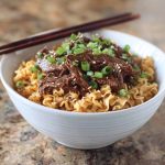 "Bowl of Korean beef noodles with tender beef slices, vegetables, and sesame seeds in a savory sauce"