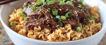 "Bowl of Korean beef noodles with tender beef slices, vegetables, and sesame seeds in a savory sauce"