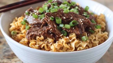 "Bowl of Korean beef noodles with tender beef slices, vegetables, and sesame seeds in a savory sauce"