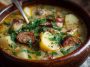 Classic German potato soup with sliced sausage, carrots, and herbs served in a rustic bowl