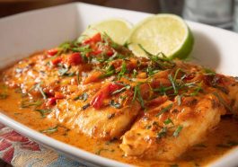 Pan-seared tilapia fillets served with vibrant roasted red pepper sauce and fresh herbs.