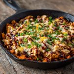 Sweet potato skillet with BBQ chicken, melted cheese, and fresh herbs served in a cast‑iron pan