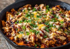Sweet potato skillet with BBQ chicken, melted cheese, and fresh herbs served in a cast‑iron pan