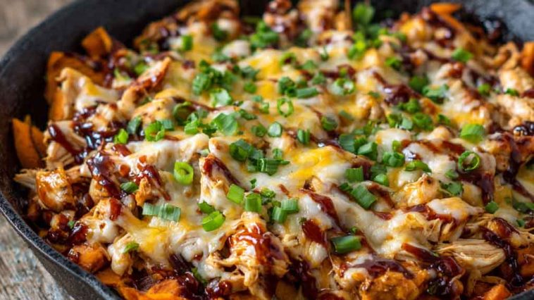 Sweet potato skillet with BBQ chicken, melted cheese, and fresh herbs served in a cast‑iron pan