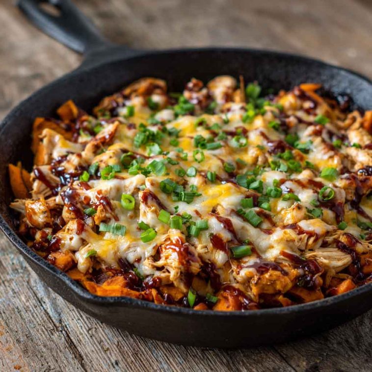 Sweet potato skillet with BBQ chicken, melted cheese, and fresh herbs served in a cast‑iron pan
