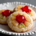 Golden pineapple upside down sugar cookie topped with caramelized pineapple rings and cherries on a dessert plate