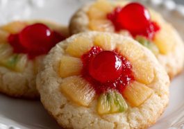 Golden pineapple upside down sugar cookie topped with caramelized pineapple rings and cherries on a dessert plate