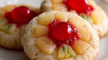 Golden pineapple upside down sugar cookie topped with caramelized pineapple rings and cherries on a dessert plate