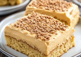 Moist peanut butter sheet cake topped with creamy peanut butter frosting, sliced into squares and served on a tray.