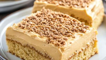 Moist peanut butter sheet cake topped with creamy peanut butter frosting, sliced into squares and served on a tray.