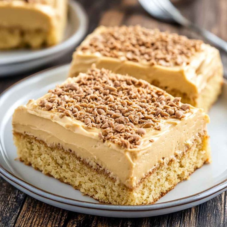Moist peanut butter sheet cake topped with creamy peanut butter frosting, sliced into squares and served on a tray.