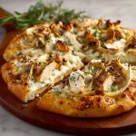 A golden-brown roasted garlic white chicken pizza topped with melted mozzarella, tender chicken pieces, and fresh herbs on a crispy crust.