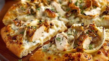 A golden-brown roasted garlic white chicken pizza topped with melted mozzarella, tender chicken pieces, and fresh herbs on a crispy crust.