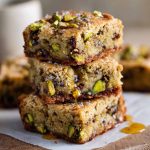 Golden brown butter pistachio cookie bars drizzled with honey and topped with chopped pistachios.