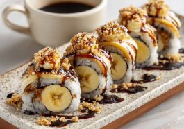 Slices of banana sushi topped with peanut butter, chocolate drizzle, and sprinkled with coconut flakes, arranged neatly on a plate.