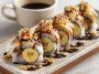 Slices of banana sushi topped with peanut butter, chocolate drizzle, and sprinkled with coconut flakes, arranged neatly on a plate.