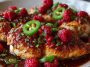 “Grilled chicken topped with sweet raspberry glaze and spicy jalapeño slices, garnished with fresh herbs.”