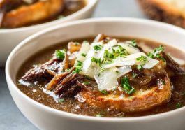 French onion short rib soup topped with melted Gruyère toast served in a rustic bowl with caramelized onions and herbs