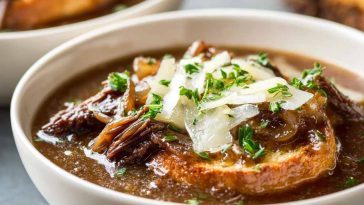 French onion short rib soup topped with melted Gruyère toast served in a rustic bowl with caramelized onions and herbs