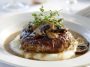 Homemade Salisbury steak served with rich mushroom gravy, mashed potatoes, and fresh parsley garnish on a dinner plate.