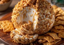 Reese’s cheese ball dessert made with peanut butter, cream cheese, and chocolate chips, rolled in crushed Reese’s candies and served with graham crackers.