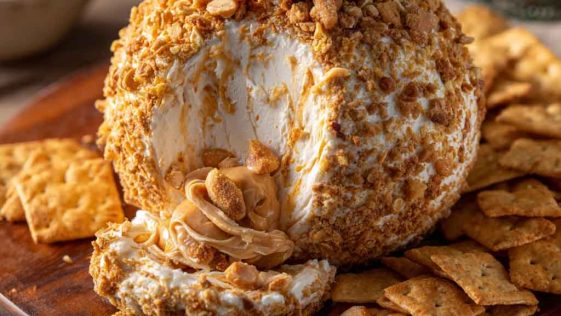 Reese’s cheese ball dessert made with peanut butter, cream cheese, and chocolate chips, rolled in crushed Reese’s candies and served with graham crackers.