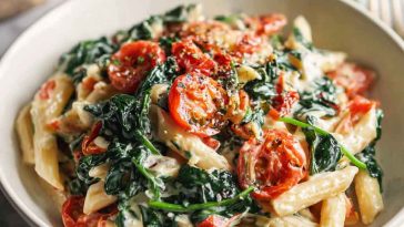 Creamy spinach tomato pasta with penne, fresh spinach, cherry tomatoes, and a rich garlic cream sauce served in a rustic bowl.