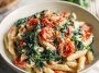 Creamy spinach tomato pasta with penne, fresh spinach, cherry tomatoes, and a rich garlic cream sauce served in a rustic bowl.