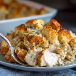 Golden baked chicken with savory stuffing, served hot in a casserole dish, garnished with fresh herbs.