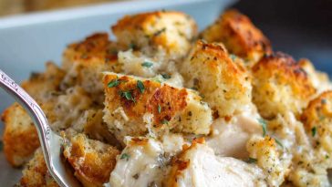 Golden baked chicken with savory stuffing, served hot in a casserole dish, garnished with fresh herbs.