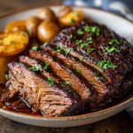Juicy slow cooker brisket sliced with rich gravy, served with roasted vegetables.