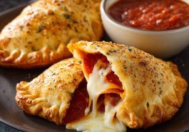 Golden Pillsbury pizza calzones on a plate with marinara dipping sauce