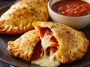 Golden Pillsbury pizza calzones on a plate with marinara dipping sauce