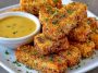 Golden honey mustard tofu tenders baked until crispy, served with dipping sauce and garnished with fresh herbs.