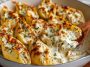 Golden baked garlic butter chicken Alfredo stuffed shells filled with creamy chicken, ricotta, and Alfredo sauce, topped with melted cheese in a casserole dish.