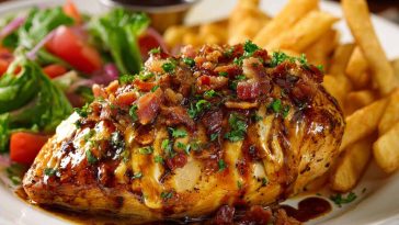 Juicy Alice Springs chicken topped with crispy bacon, melted cheese, and honey mustard sauce, inspired by Outback Steakhouse, served on a plate.