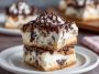 Creamy cannoli cheesecake bars topped with mini chocolate chips and powdered sugar on a golden graham cracker crust.