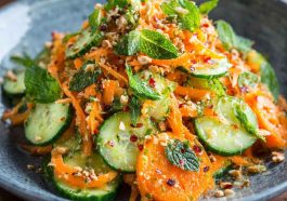 Asian carrot and cucumber salad with sesame seeds, fresh herbs, and sesame-soy dressing in a bowl.