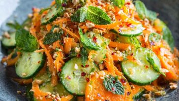 Asian carrot and cucumber salad with sesame seeds, fresh herbs, and sesame-soy dressing in a bowl.