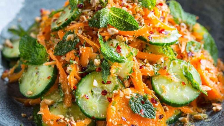 Asian carrot and cucumber salad with sesame seeds, fresh herbs, and sesame-soy dressing in a bowl.