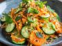 Asian carrot and cucumber salad with sesame seeds, fresh herbs, and sesame-soy dressing in a bowl.