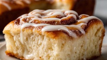 Golden cinnamon roll focaccia topped with icing drizzle on a baking tray