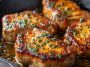 Garlic butter pan-seared pork chops with a golden crust, topped with herbs and a rich buttery sauce.