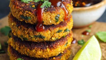 Healthy sweet potato lentil patties golden and crispy on the outside, served with a dipping sauce and fresh herbs.