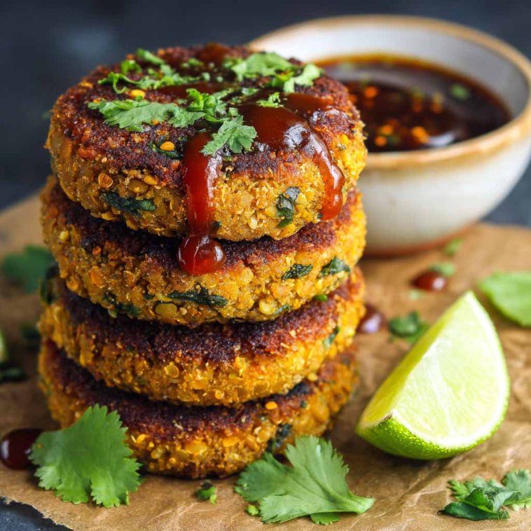 Healthy sweet potato lentil patties golden and crispy on the outside, served with a dipping sauce and fresh herbs.